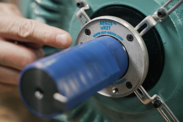 A maintenance technician installing a split-design shaft grounding ring onto an existing industrial motor shaft without decoupling the load.
