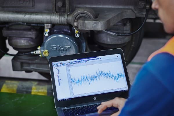 Engineer using a handheld sensor to monitor motor bearing health and vibration levels to ensure workplace safety.