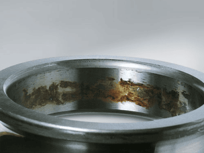 Close-up of a damaged wind turbine generator bearing raceway showing severe corrosion, pitting, and electrical fluting (washboard) lines on the inner raceway.