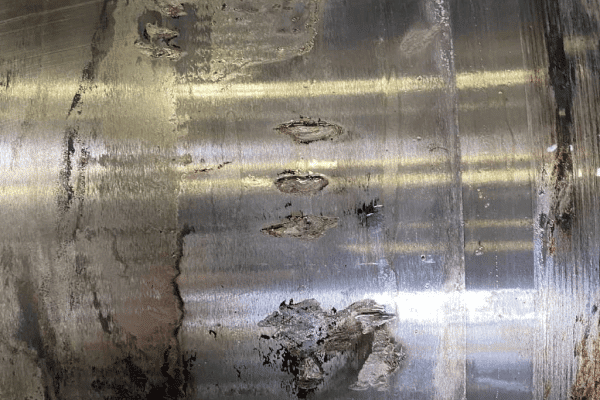 Close-up view of severe electrical pitting and spalling damage on a wind turbine main bearing raceway.